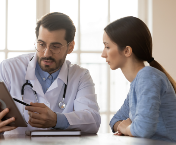 Doctor holding a clipboard talking to a young lady